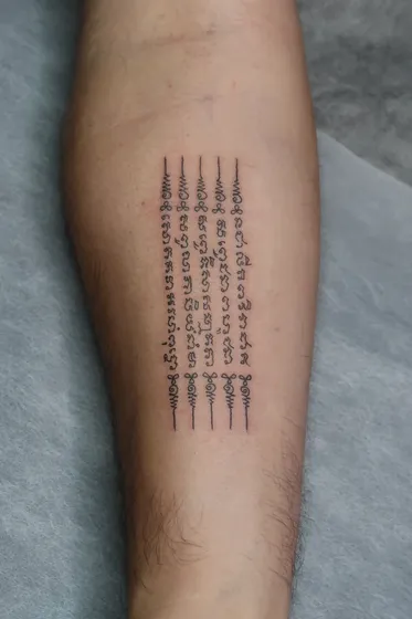 Five lines of Khom yantra script down the inner forearm