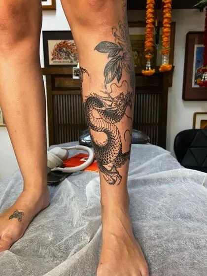 Japanese dragon tattoo on the shin and lower leg in black and grey