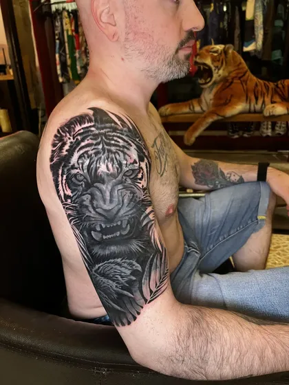 Finished tiger cover-up, guest seated next to a tiger statue in the studio