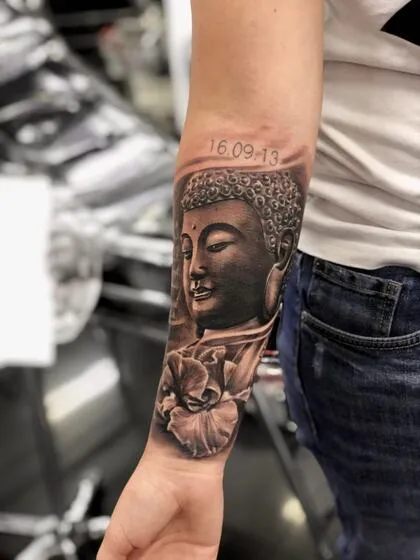 Realism Buddha face and lotus flower forearm tattoo