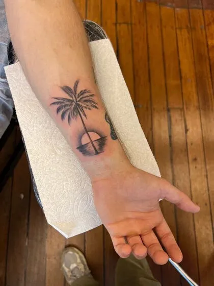 Black and grey palm tree and sunset wrist tattoo