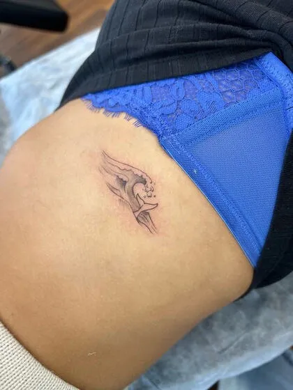 Fine line whale tail and wave hip tattoo