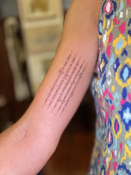 Five lines of Khom yantra script along the inner upper arm