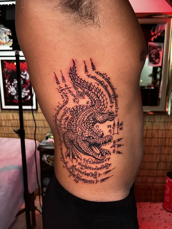 Crocodile yantra framed by Khom script tattooed on the ribs, Beach Street Arts Phuket