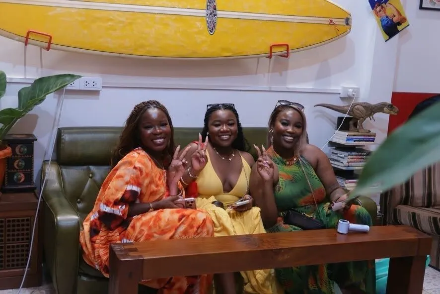 Guests on the green leather sofa under a surfboard